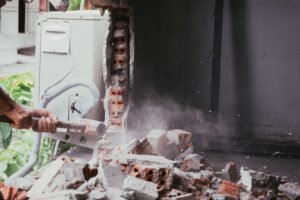 unrecognizable builder using a sledgehammer breaking and smashing the wall fallen into debris breaking wall and challenges concept